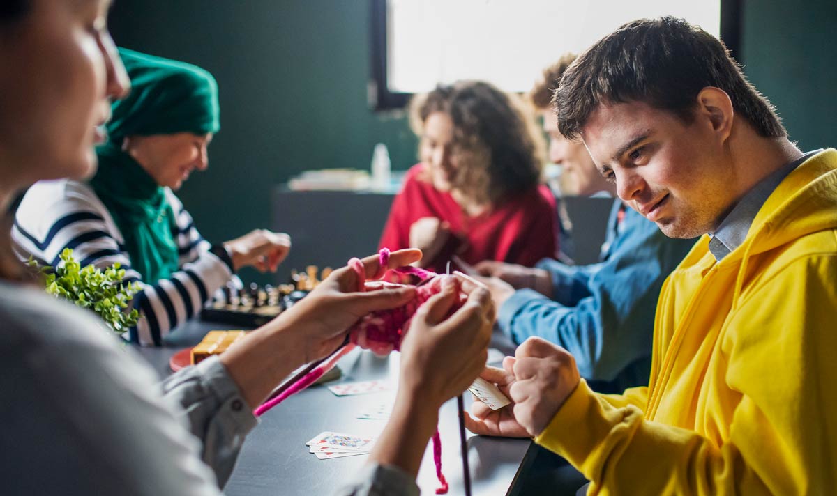 Gruppe von Menschen, die Karten und Brettspiele im Gemeindezentrum spielen, Inklusivität behinderter Menschen